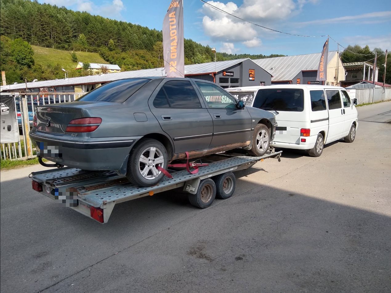 Sivý Peugeot 406 naložený na prívese